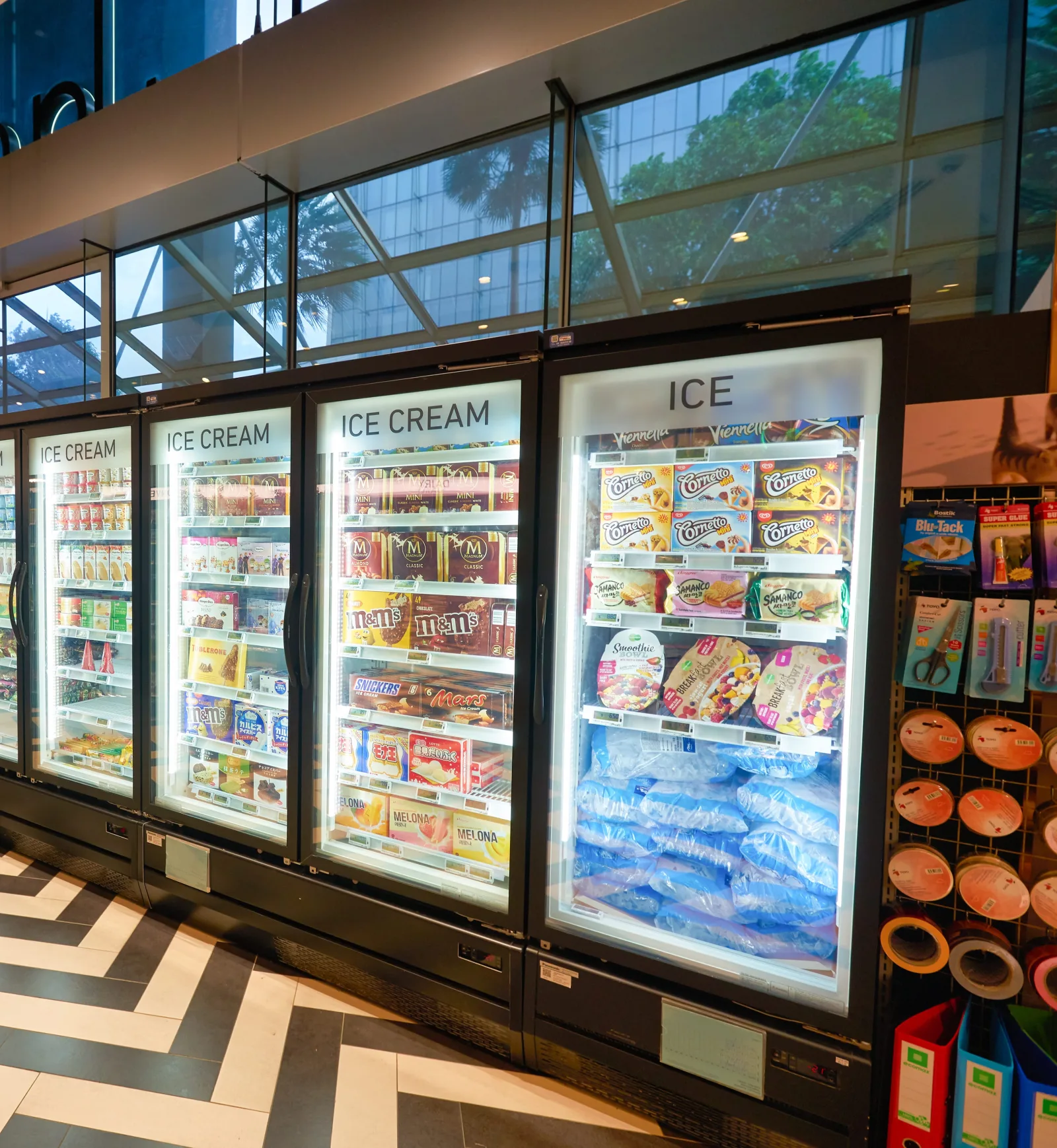 Supermarktgangpad met een zwart-wit visgraatvloer en een rij vrieskisten